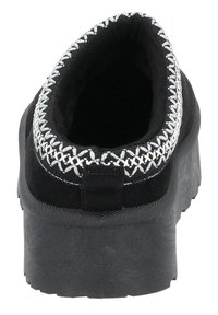Svart slip-on sko med en texturerad gummisula, ett broderat silvermönster runt kragen och en slät innersula.