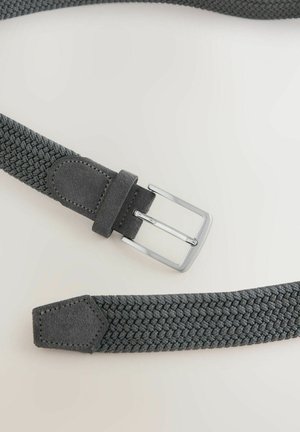 Sötétszürke szövött szövet öv nubuk béléssel és ezüst fém csattal, laposan elhelyezve egy világos felületen.