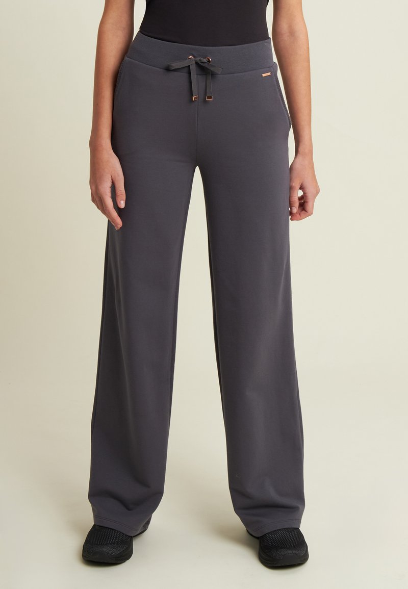 Pantalones de pierna ancha grises, confeccionados en tejido suave, con cintura elástica, cordón de ajuste con herrajes metálicos y bolsillos laterales.