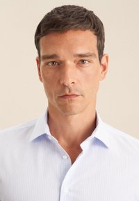 Camicia azzurro chiaro con motivo, con colletto ad allacciatura, realizzata in cotone. Presenta un design geometrico sottile e una vestibilità standard.