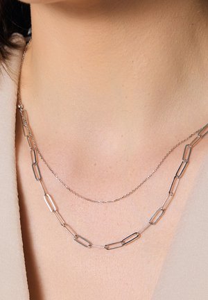 Srebrny naszyjnik z dwoma warstwami: jedna z wydłużonymi ogniwami w kształcie spinacza, a druga delikatnym łańcuszkiem. Gładka tekstura i minimalistyczny design.