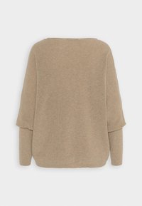 Gebreide trui in beige met een losse pasvorm, brede halslijn en vleermuismouwen. De textuur is geribbeld, wat zorgt voor een zachte uitstraling en gevoel.