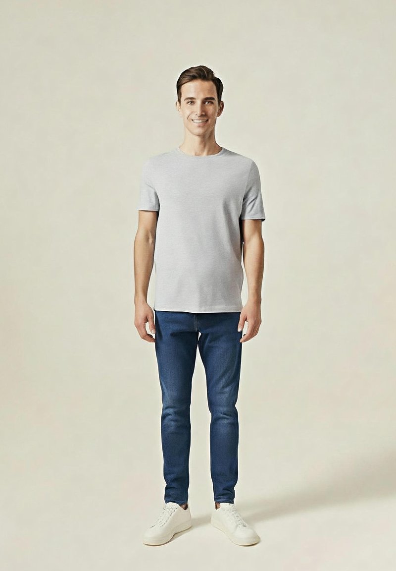 Szary T-shirt z krótkim rękawem w połączeniu z ciemnoniebieskimi dżinsami o slim fit i białymi sneakersami. Prosty design, bez widocznych wzorów czy ozdobnych elementów.