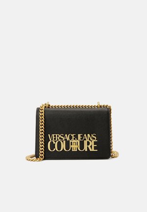 Sac bandoulière rectangulaire noir avec une bandoulière chaîne dorée et un logo doré audacieux "Versace Jeans Couture" à l'avant.