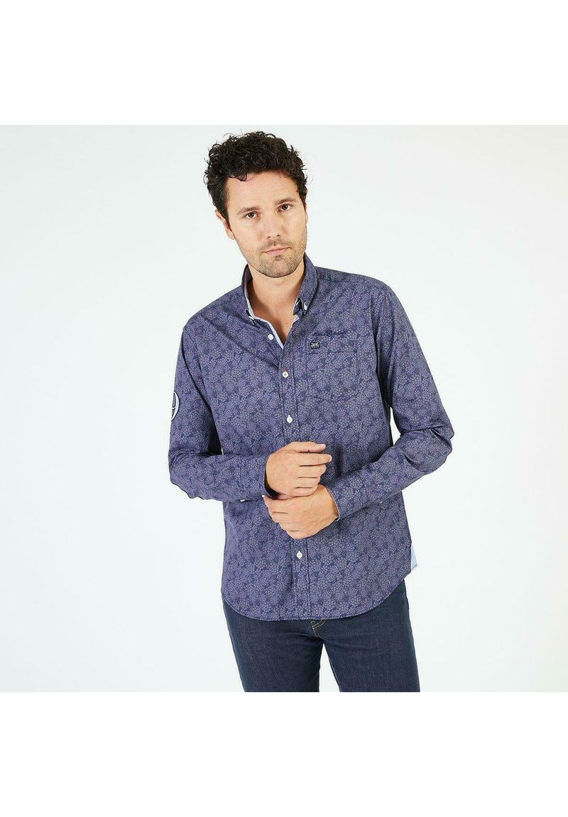 Chemise à manches longues boutonnée en violet foncé avec un motif floral. Dotée d'un col contrastant et d'un logo brodé sur la poitrine.