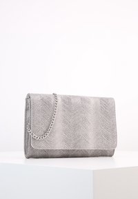 Sølv clutch pung med en herringbone struktur, et klaplås og en kædestrop til bæring. Har en glat overflade og et minimalistisk design.