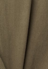 Gros plan d’un tissu brun plié avec une texture fine de sergé diagonal.