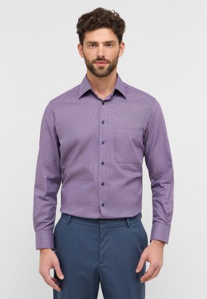 Lila karierte Hemdbluse mit langen Ärmeln und einem button-down Kragen, ausgestattet mit dunklen Knöpfen und einer Brusttasche, kombiniert mit blauen Hosen.
