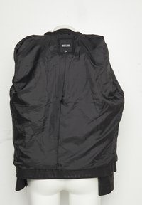 Giacca nera girata al rovescio su un manichino, che mostra la fodera in tessuto lucido e l'etichetta "ONLY & SONS" nella parte superiore centrale sul retro.