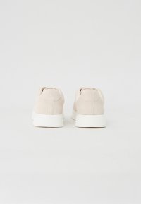 Lys rosa semskede sneakers med hvite gummisåler, med en glatt tekstur, avrundet form og minimalistisk design uten synlig merkevare.