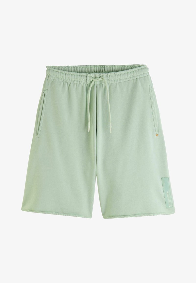 Shorts en coton vert clair avec une taille élastique, fermeture à cordon, poches latérales et un accent rectangulaire en bas de la jambe gauche.