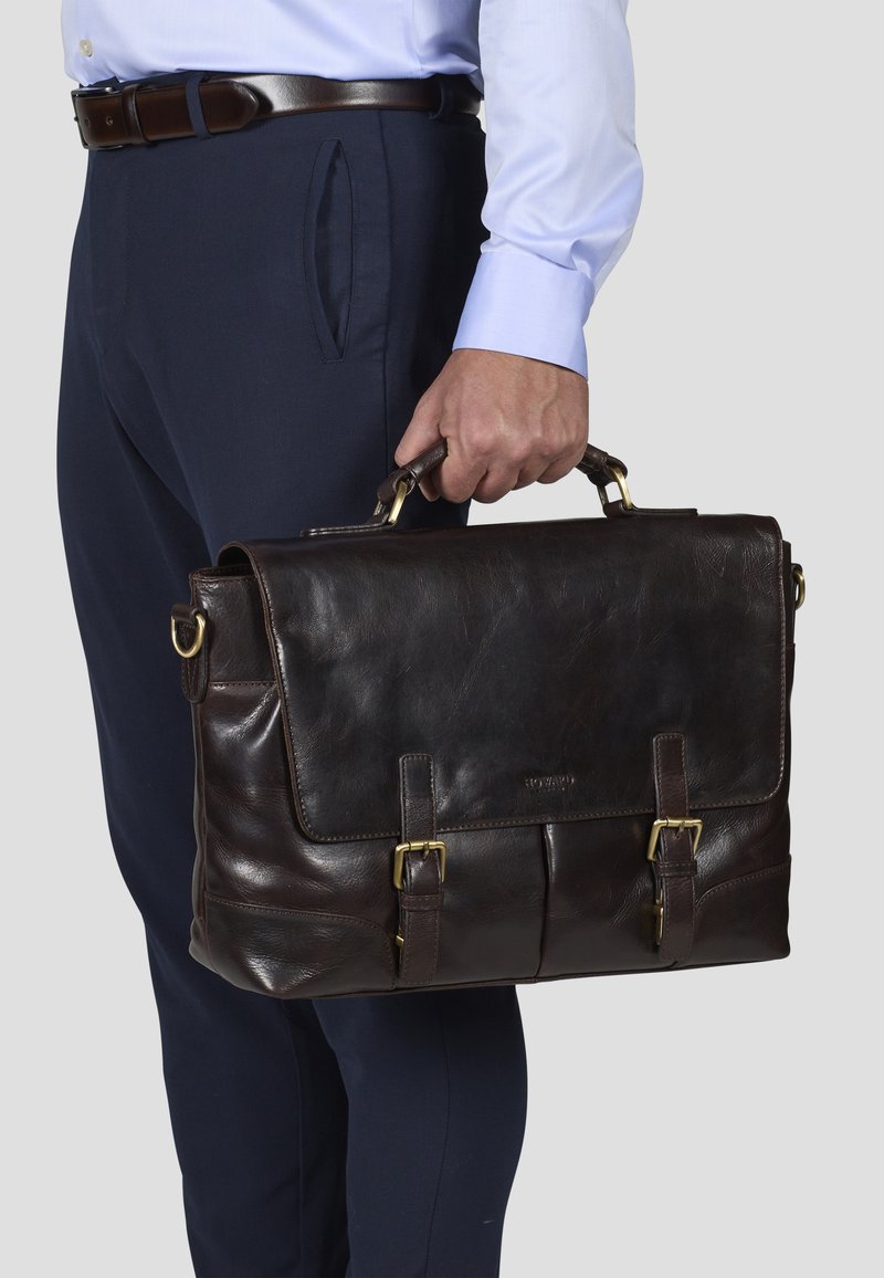 Brown leather briefcase with a front flap, two buckles, and top handle. Smooth texture, rectangular shape, and gold-tone hardware accents.