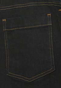 Zwarte denim stof met een achterzak met oranje stiksels en een licht gestructureerd oppervlak. Compact ontwerp met minimale detailing.