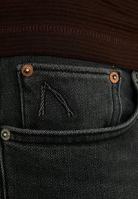 Tmavé džíny z denimu s texturovaným povrchem, které mají výšivku loga na kapse a kovové nýty pro zesílení.