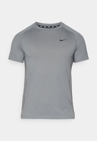 Harmaa urheilupaita, valmistettu kevyestä materiaalista, pyöreällä pääntiellä, lyhyillä hihoilla ja mustalla Nike-logolla rinnassa.