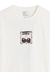 T-shirt crema in cotone con una stampa grafica nera di due ciliegie all'interno di una cornice decorativa. Il collo è rotondo e grezzo.