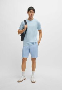 Light blue textured t-shirt, paired with light blue shorts, white athletic shoes, and white socks, with a black shoulder bag.