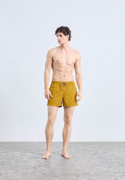 Férfi úszónadrág mustár sárga színben, könnyű anyagból készült. Állítható zsinór a derékrésznél és oldalzsebekkel ellátva.