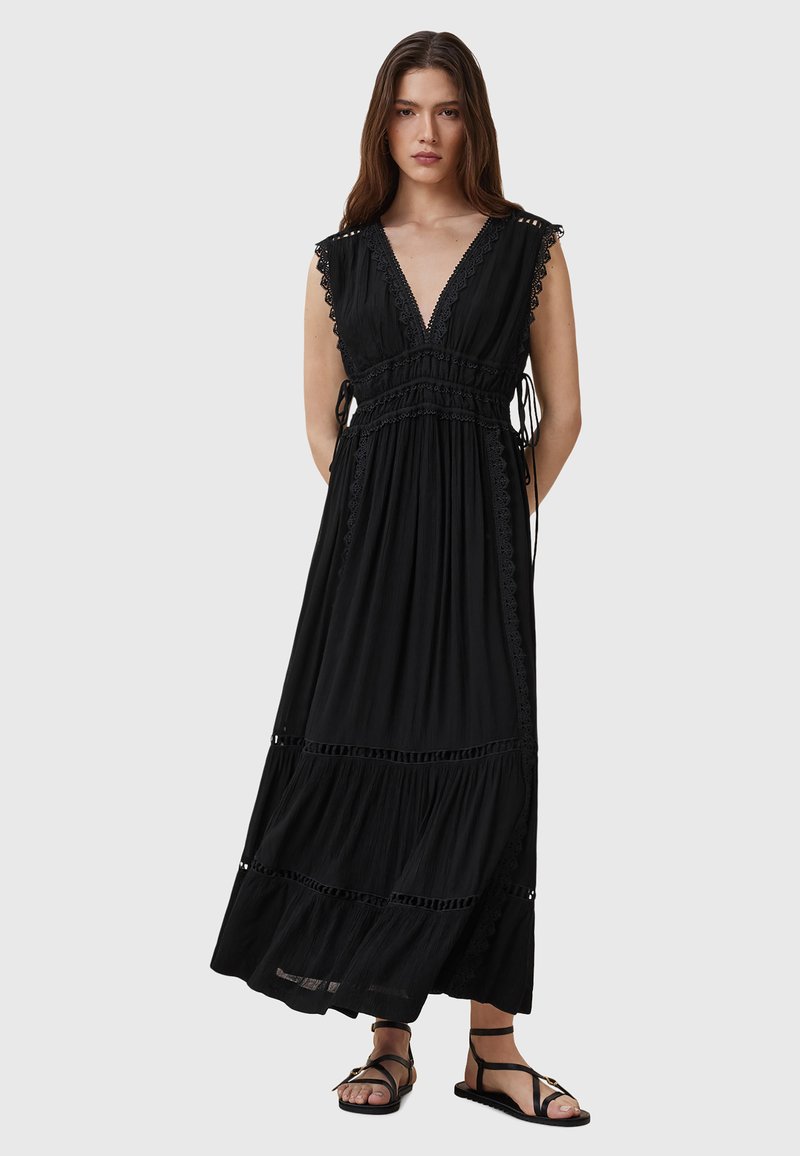 Abito maxi nero con scollo a V, bordo in pizzo e design a strati. Presenta lacci regolabili in vita e sandali piatti.