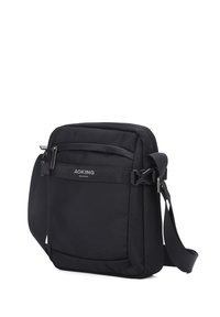 Borsa a tracolla nera realizzata in tessuto testurizzato, dotata di una tracolla regolabile, tasca frontale con zip e discreto dettaglio del logo sul davanti.