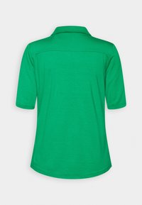 Polo vert à manches courtes vu de dos, avec un col standard et un ourlet arrondi sur fond blanc.