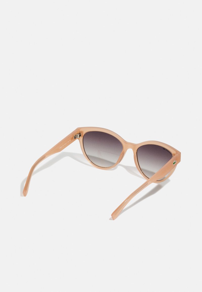 Occhiali da sole con una montatura in plastica morbida color pesca, forma a occhio di gatto, lenti scure sfumate e aste sottili con un delicato dettaglio di branding.