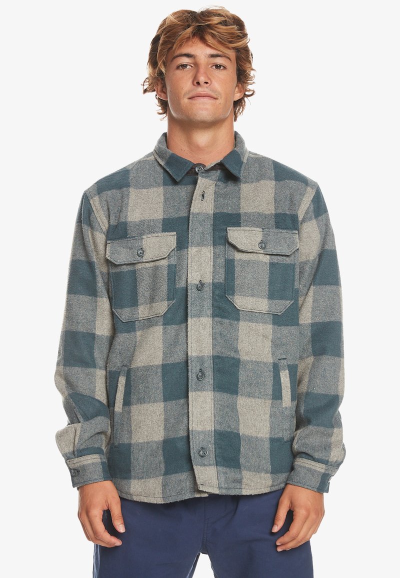 Groen en grijs geblokt flanellen shirt met knoopsluiting aan de voorkant, twee borstzakken en knoopmanchetten. Zachte textuur, standaard kraag en een ontspannen pasvorm.