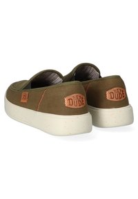 Olijfgroene instap schoenen van stof met een wit gespikkelde zool. Beschikt over een "HEY DUDE" logo patch op de hiel, met een gestructureerd stiksel detail.