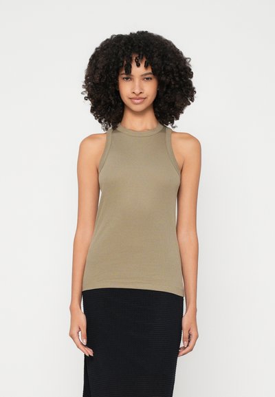 Olivgrünes, geripptes Tanktop mit hohem Kragen und ärmellosem Design, kombiniert mit einem strukturierten schwarzen Rock, der eine figurbetonte Silhouette schafft.