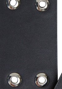El material negro texturizado presenta cinco ojales metálicos. La superficie parece suave con un patrón ligeramente elevado, lo que mejora el agarre y la durabilidad.