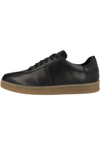 Zapatilla de cuero negro con punta redonda, superficie texturizada y suela de goma color caramelo. Cuenta con cordones planos negros y un diseño de tobillo bajo.