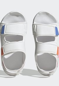 Sandali bianchi con due cinturini regolabili, caratterizzati da sezioni ritagliate. Accenti in blu, arancione e rosa. Suola interna testurizzata per il comfort.
