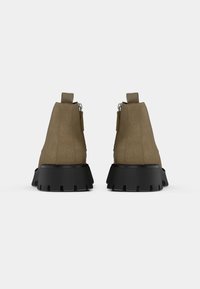 Rudi džinsiniai auliniai batai su tvirtu juodu guminės padą, su užtrauktuku gale ir maža kilpa lengvam užsidėjimui.