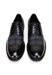 Leren en geruite stoffen dresschoenen, met een gepolijste zwarte leren neus en brogue-details, voorzien van grijze en blauwe geruite accenten.