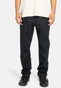 Sorte, afslappede bukser i bomuld med en glat tekstur og standardlommer. Båret med sorte sneakers.