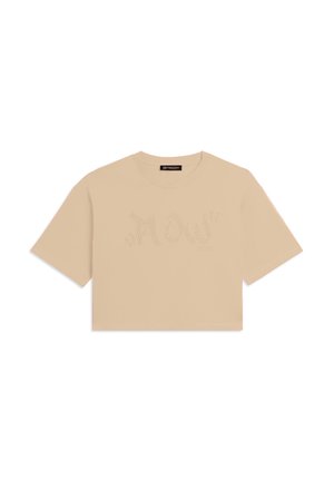 Camiseta corta beige con mangas cortas y "Flow" escrito en pequeñas piedras de strass estilizadas a lo largo del pecho.