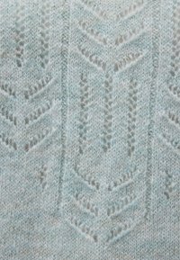 Helles blaues Strickgewebe mit einem strukturierten Zickzackmuster. Weiche, flauschige Textur mit sichtbaren Nähten, die ein geschichtetes Erscheinungsbild erzeugen.