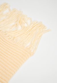 Gebreide sjaal van zacht, lichtgeel stof met een gestructureerd, geribbeld patroon; voorzien van lange, franjes aan de randen voor extra detail.