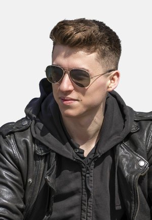 Black leather jacket with silver hardware, black hoodie underneath, and aviator sunglasses. Short, styled light brown hair and neutral background.