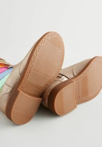 Botas de oro rosa con suela plana que presentan paneles coloridos de azul, rosa, naranja y verde. La suela tiene un diseño texturizado y patrimonial.