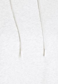 Hoodie grigio chiaro con tessuto texturizzato, presenta una cerniera e coulisse, ciascuna termina con una punta plastica bianca.