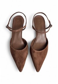 Talons slingback en suède marron avec des bouts pointus et un talon plat. Elles ont une fine bride à la cheville et une semelle intérieure en cuir lisse.