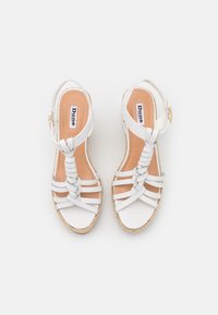 Sandali bianchi in pelle con fasce incrociate e una soletta color nocciola. Caratterizzati da una suola a zeppa con una texture intrecciata e una cinghia alla caviglia regolabile.