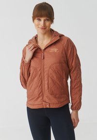Veste matelassée couleur rouille avec fermeture à zip, capuche et deux poches avant. Présente des poignets côtelés et un emblème de logo sur la poitrine.