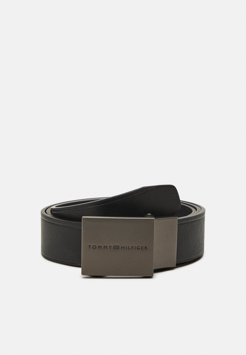 Cinturón de cuero negro con una hebilla metálica cuadrada que presenta un logo en relieve. Textura suave con un diseño clásico y minimalista.