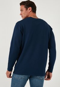 Maglietta a maniche lunghe blu navy in cotone misto, con collo rotondo, tessuto liscio e sottili spacco laterale all'orlo.