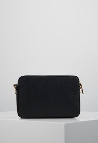 Czarna prostokątna torba wykonana z teksturowanego materiału. Posiada złoty zamek błyskawiczny i odpinany pasek. Gładka powierzchnia z zaokrąglonymi brzegami.