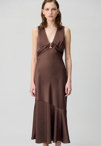 Robe en satin marron avec un décolleté en V profond, détail avant torsadé et ourlet évasé. Texture lisse avec un léger éclat et des éléments de design minimalistes.