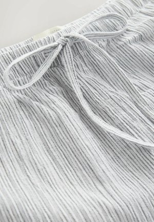 Baltos trumpikės su vertikaliu tekstūruotu dryžuotu raštu, su elastine juosmenine dalimi ir raišteliu.