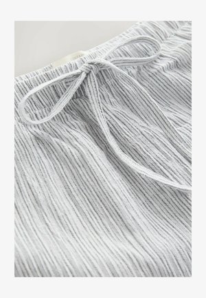 Valged lühikesed püksid, millel on tekstuuriga vertikaalsed triibud, elastse vöökoha ja nööriga seotud detail.